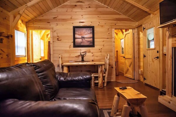 L’int érieur d’un chalet en bois, avec un canapé en cuir, une table à manger et une cheminée.