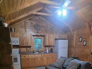 A wooden cabin interior with a kitchen, a dining area, and a living room.