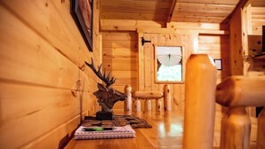 A wooden interior with a wooden bench, a table with a book and a pen, and a window with a view. - Whippoorwill at Avenwood Cabins (new straitsville)