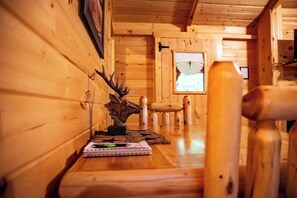Un intĂ©rieur en bois avec un banc en bois, une table sur laquelle se trouvent un livre et un stylo, et une fenĂȘtre donnant sur un paysage.
