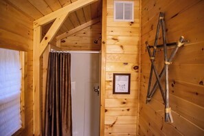 Un intérieur en bois avec une porte, une fenêtre avec des rideaux et une échelle appuyée contre le mur.