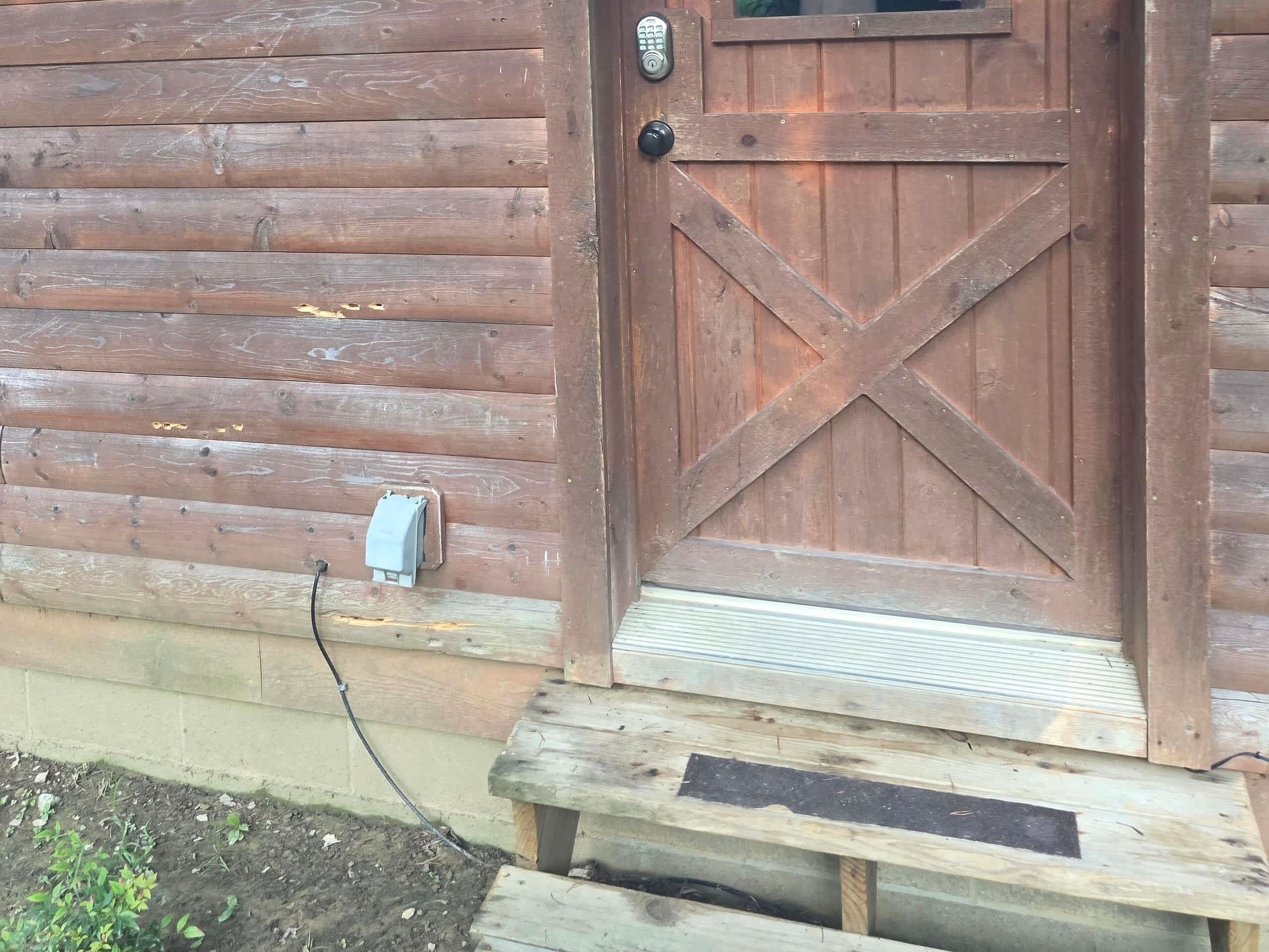 Een houten deur met een metalen handgreep en een brievenbus op de muur.