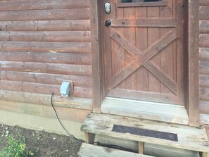 A wooden door with a metal handle and a small mailbox on the wall.