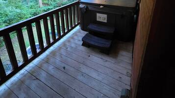 Um deck de madeira com churrasqueira e lixeira.