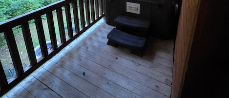 Eine Holzterrasse mit Grill und Mülleimer.