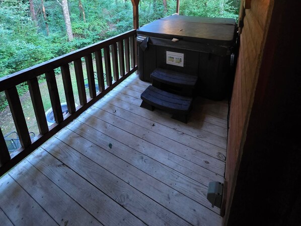 A wooden deck with a grill and a trash can.