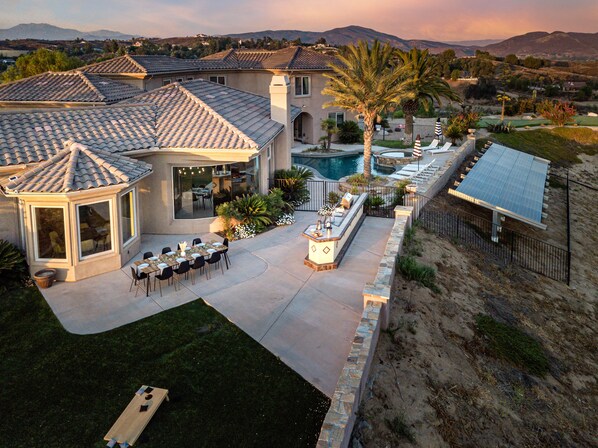 A residential property with a swimming pool, outdoor dining area, and a covered patio.