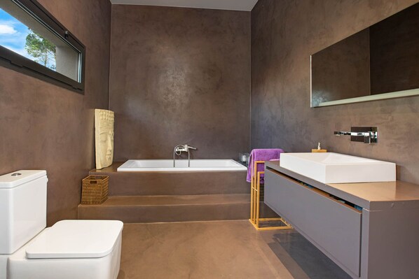 A modern bathroom with a bathtub, a toilet, and a vanity with a mirror. - 2CAST01 - Spectacular house with private pool and stunning sea views located in a quiet residential area just 3 km from the beach (Lloret de Mar)