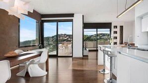 A modern kitchen with a large island, white cabinetry, and a view of a hillside.