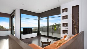 A modern living room with a large window, a flat-screen TV, and a sofa.
