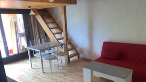 A modern living space with a wooden staircase, a dining area with a table and chairs, and a red sofa. - Sureggio Village (Capriasca)