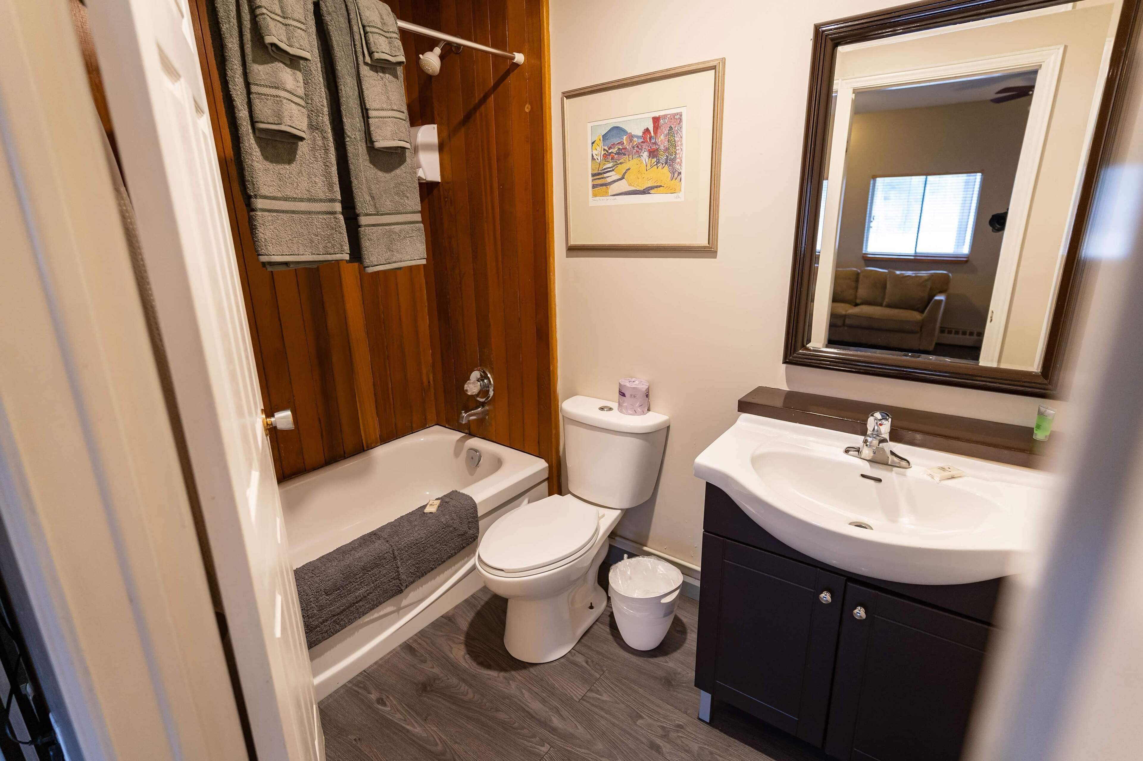 Ein Badezimmer mit Badewanne, Toilette, Waschbecken und einem gerahmten Bild an der Wand.