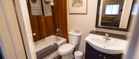 Ein Badezimmer mit Badewanne, Toilette, Waschbecken und einem gerahmten Bild an der Wand.