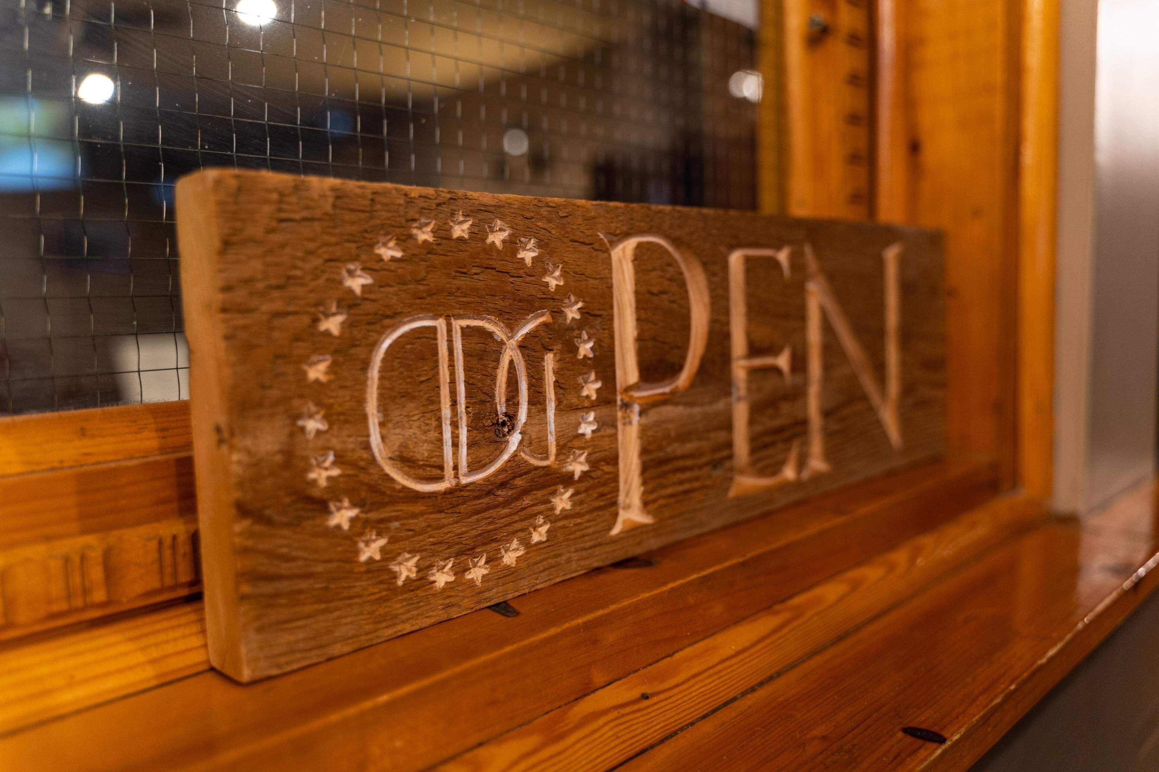 A wooden sign with "OPEN" written on it, surrounded by stars.