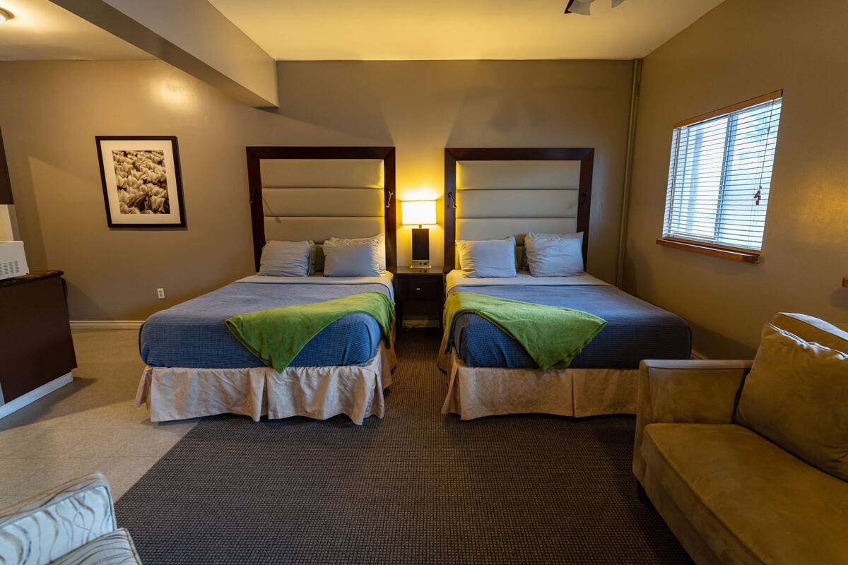 Una habitación de hotel con dos camas, un escritorio, una silla y una ventana.