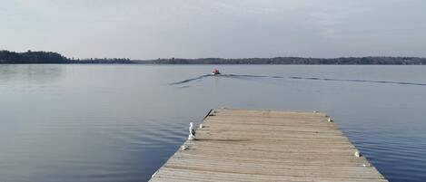 A wooden pier extending into calm water with a clear sky above.