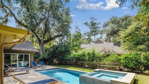 A backyard with a swimming pool, lounge chairs, and a covered patio area.