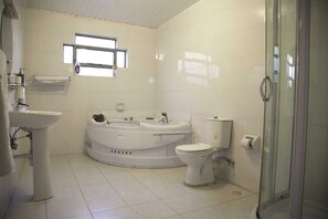 Een bad/douchecombinatie, handdoeken, zeep, toiletpapier