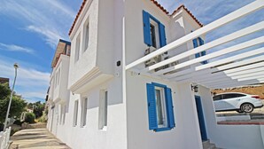 A white building with blue shutters and a white car parked in front. - Bozcaada Teras Otel (Bozcaada)