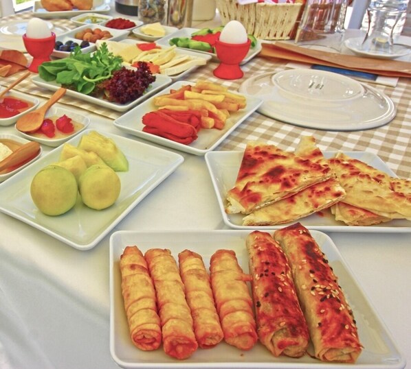 A buffet with various dishes including fruits, vegetables, and rolls. - Bozcaada Teras Otel (Bozcaada)