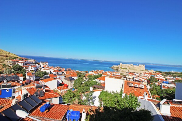 A coastal town with red-tiled rooftops, a prominent castle, and a clear view of the sea. - Bozcaada Teras Otel (Bozcaada)