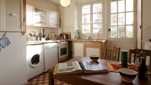 Une cuisine équipée d’un lave-linge, d’un four et de meubles de rangement en bois.