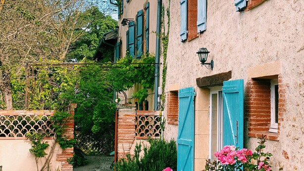 Il s’agit d’un bâtiment traditionnel, avec un chemin de gravier, une clôture en bois et un petit jardin agrémenté de fleurs roses.