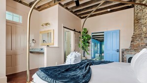 Un dormitorio con cama, techo de madera, puerta azul y una planta.