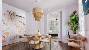 Un comedor con una mesa redonda y seis sillas, una planta grande y una pared con papel tapiz floral.