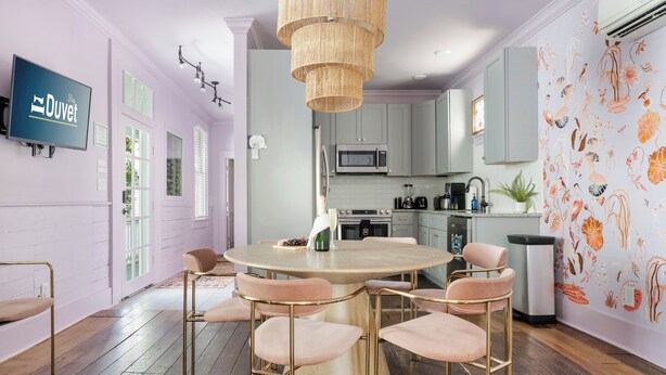 Una cocina moderna con una mesa de comedor redonda, armarios de madera clara y una lámpara colgante.