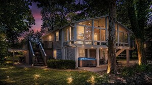 A two-story house with a hot tub, a covered patio, and a staircase leading to an upper deck. - Riverfront Home on the Ohio River, Private Dock, Hot Tub, Sleeps 8 (Prospect)