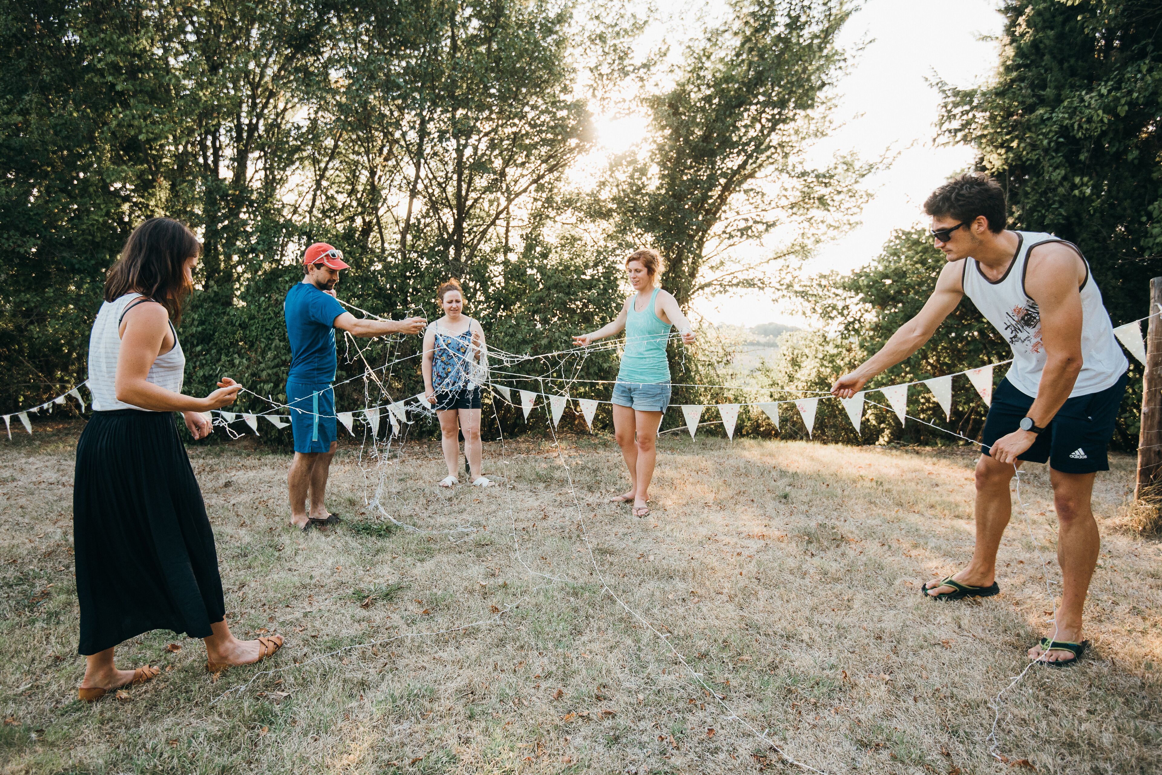 A group of people playing a game of tug-of-war in an outdoor setting with trees in the background.