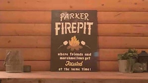 A sign on a wooden wall that reads "PARKER FIREPIT where friends and marshmallows get toasted at the same time!"