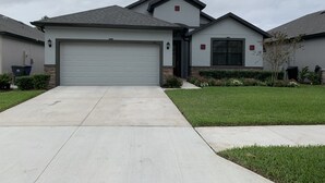 Een woonhuis met garage, oprit en een verzorgd gazon.