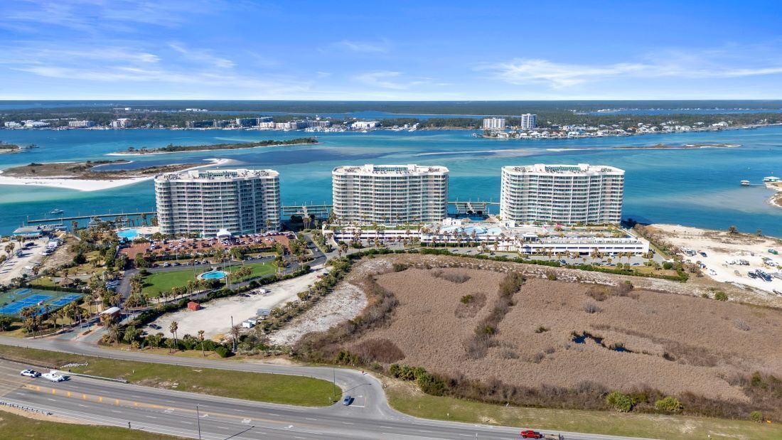 A coastal hotel complex with three high-rise buildings, a marina, and a beach area.