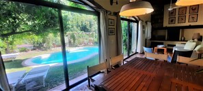 A spacious living area with a large sliding glass door leading to a swimming pool, wooden flooring, and a seating area with a TV and table. - Villa Lombrici, at Mount Camaiore foot, near to the beach with private pool (Camaiore)
