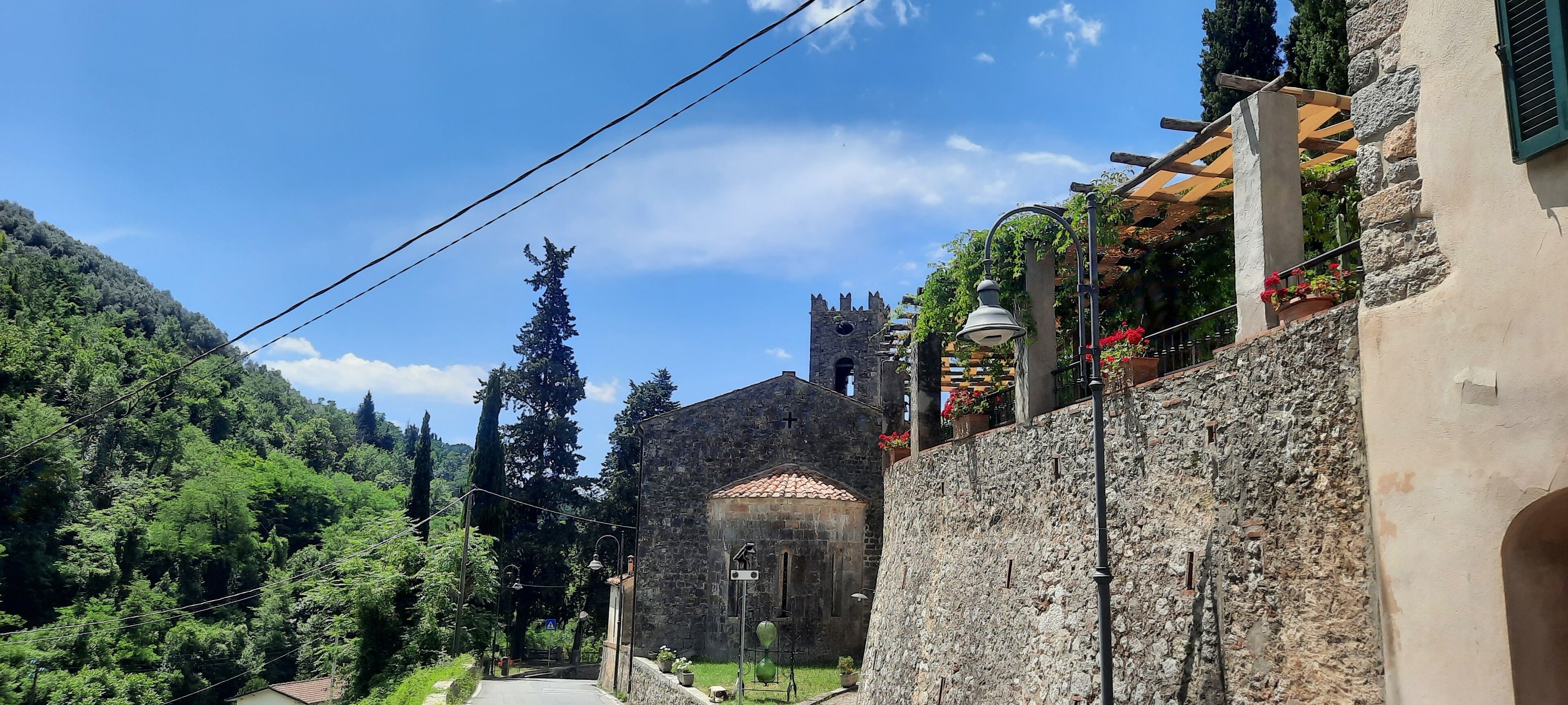 A stone building with a tiled roof, a bell tower, and a pathway leading to it.