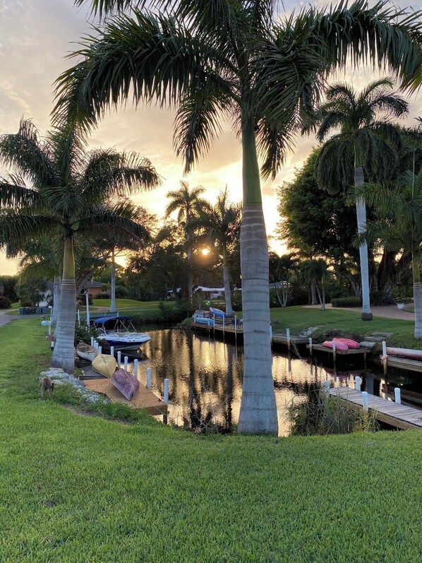 Un paysage paisible au bord d’un lac, avec des palmiers, un quai et des bateaux.