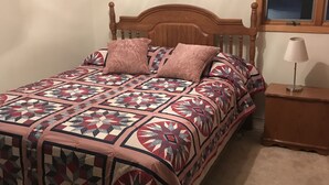 Una cama con colcha estampada, cabecero de madera y dos almohadas.