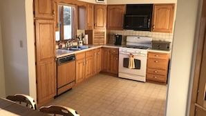 Una cocina con armarios de madera, lavavajillas, estufa, microondas y fregadero.
