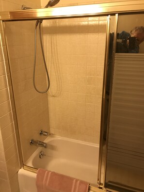 Een bad/douchecombinatie, een haardroger, handdoeken, zeep