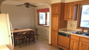 Una cocina con armarios de madera, lavavajillas, ventana con vistas y ventilador de techo.