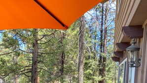 Eine Holzterrasse mit Sitzgelegenheiten im Freien, umgeben von hohen Bäumen.