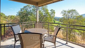 Ein Balkon mit Tisch und Stühlen, der einen schönen Ausblick auf eine Landschaft mit Bäumen und Hügeln bietet.