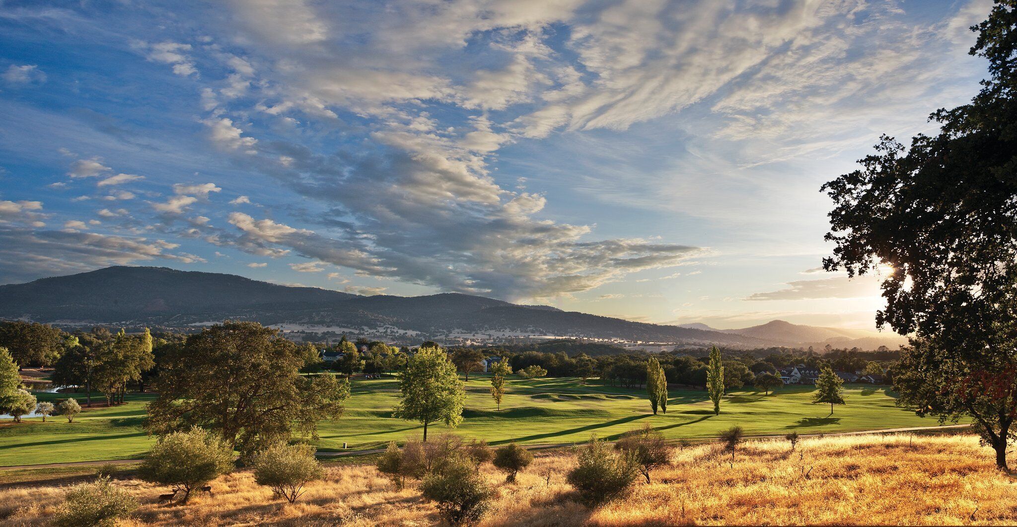 A golf course with a mountain in the background and a clear sky.