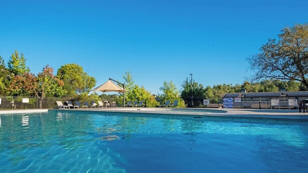 Una piscina nítida amb gandules i una zona amb ombra.