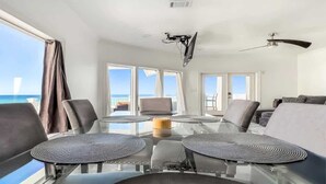 Ein moderner Essbereich mit Glastisch, mehreren Stühlen und Blick auf den Ozean.