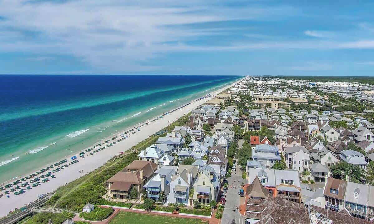 A coastal residential area with houses along the beach and a clear view of the ocean.