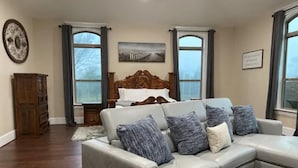 A living room with a large L-shaped sectional sofa, a wooden headboard, and a view through large windows. - NEW Hacienda Ranch W/ Resort Style Pool (Hempstead)