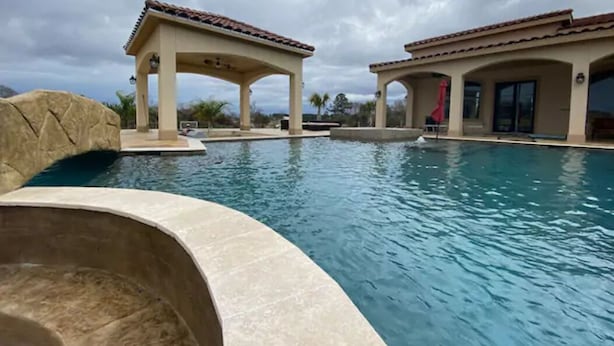 A swimming pool with two covered areas and a stone structure. - NEW Hacienda Ranch W/ Resort Style Pool (Hempstead)
